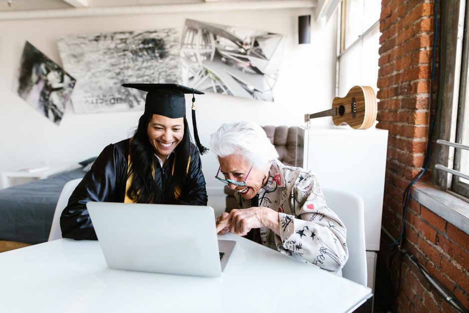 Graduate celebrating with family using a laptop for video call.